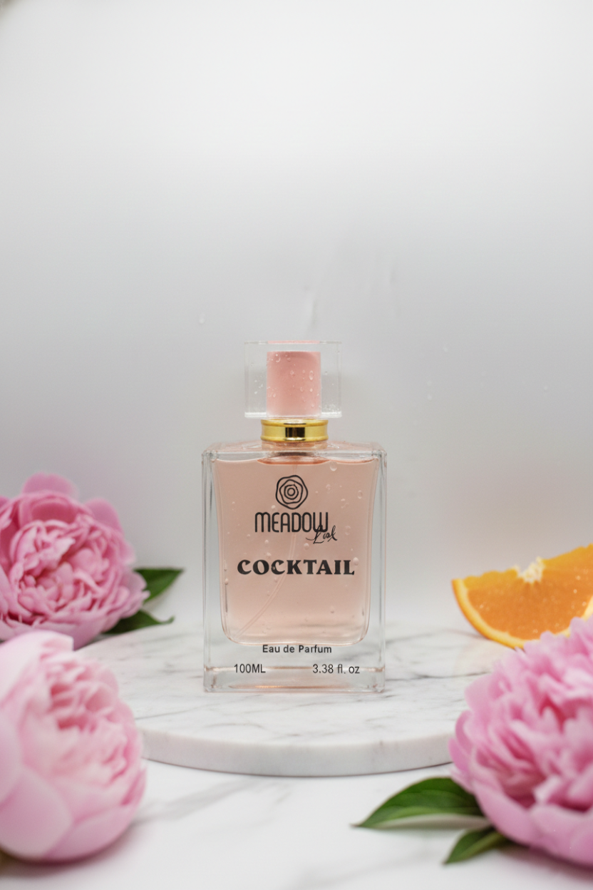 Perfume bottle labeled 'Meadow' with pink flowers and an orange slice on a white background